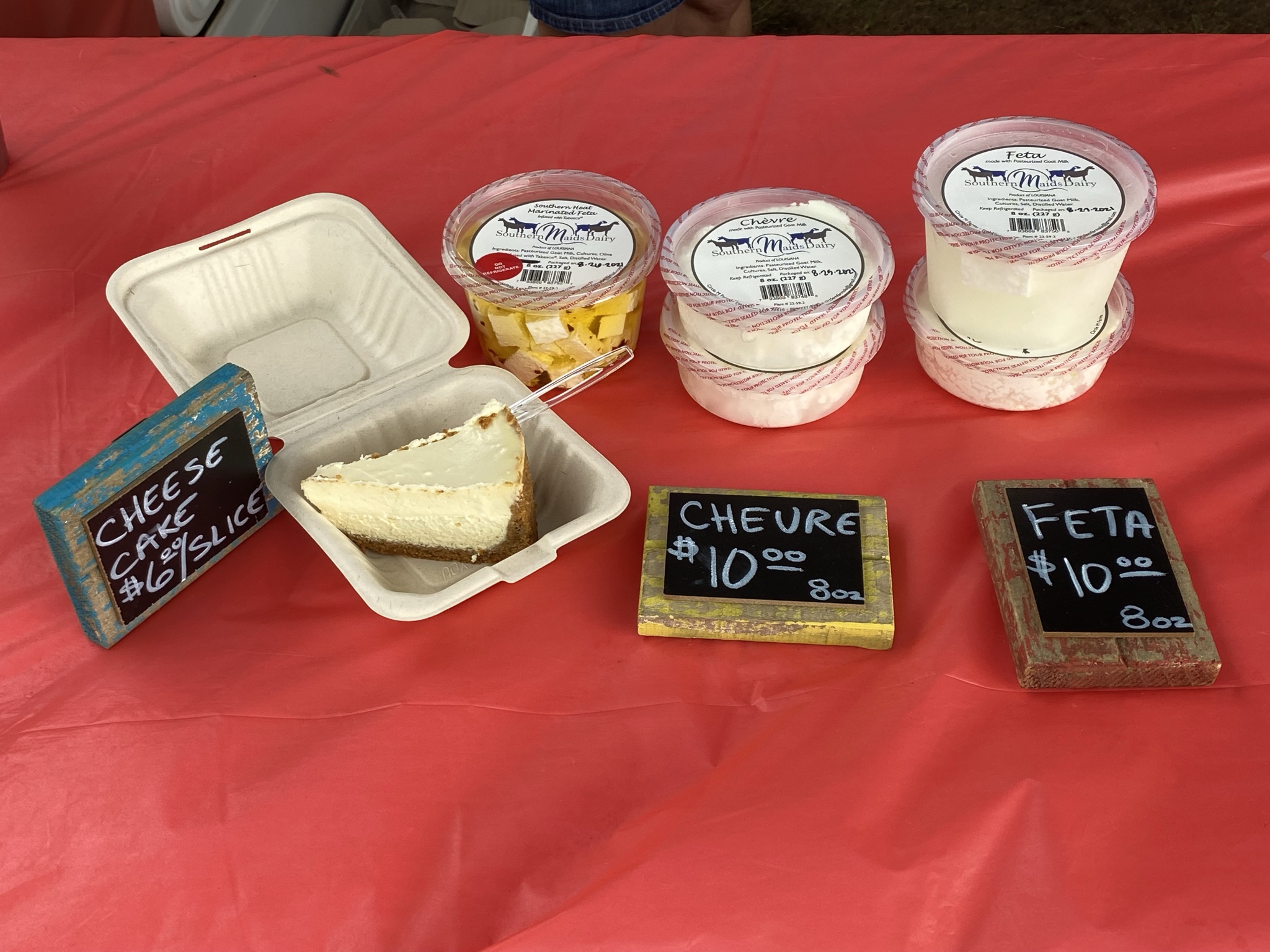 A selection of goat milk cheeses and desserts sit on a table.